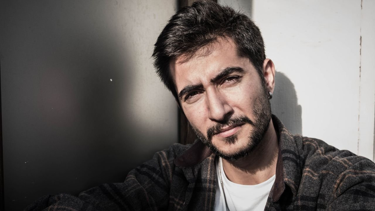 Close-up portrait of a confident man with a beard outdoors, embracing natural light.